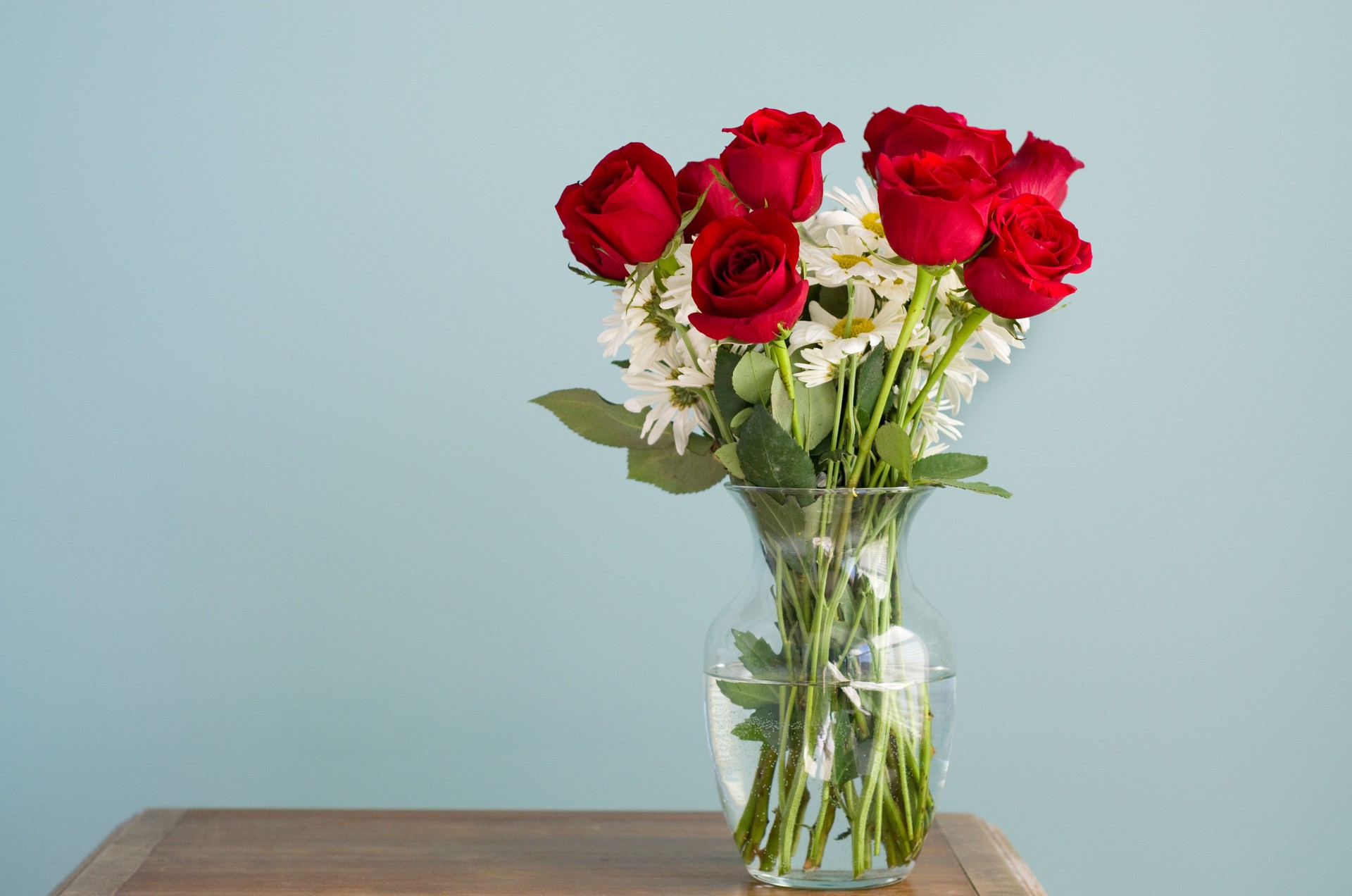 roses and daisies sit in a vase on table