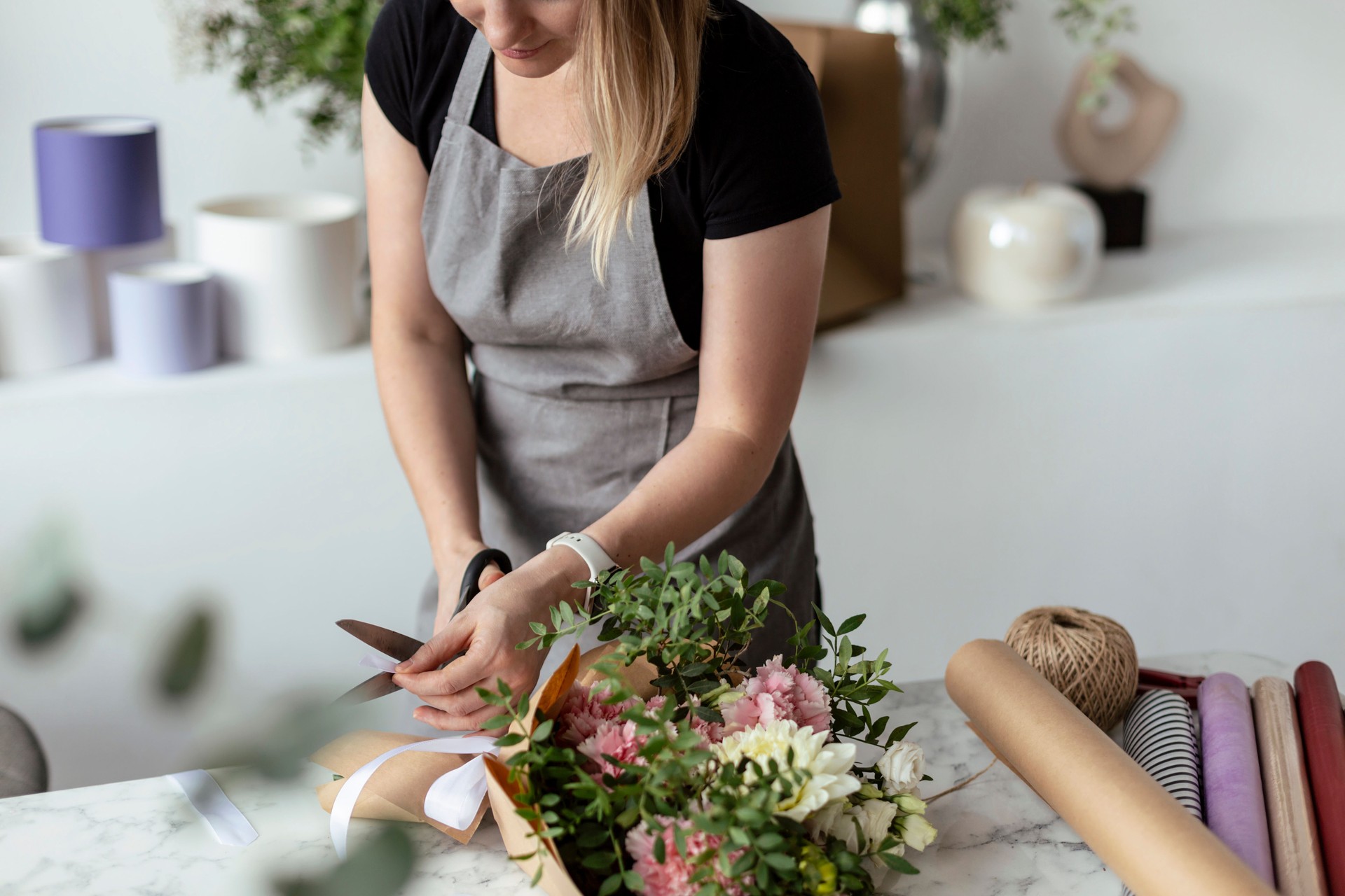 Florist at work: pretty young woman making fashion modern bouquet of different flowers