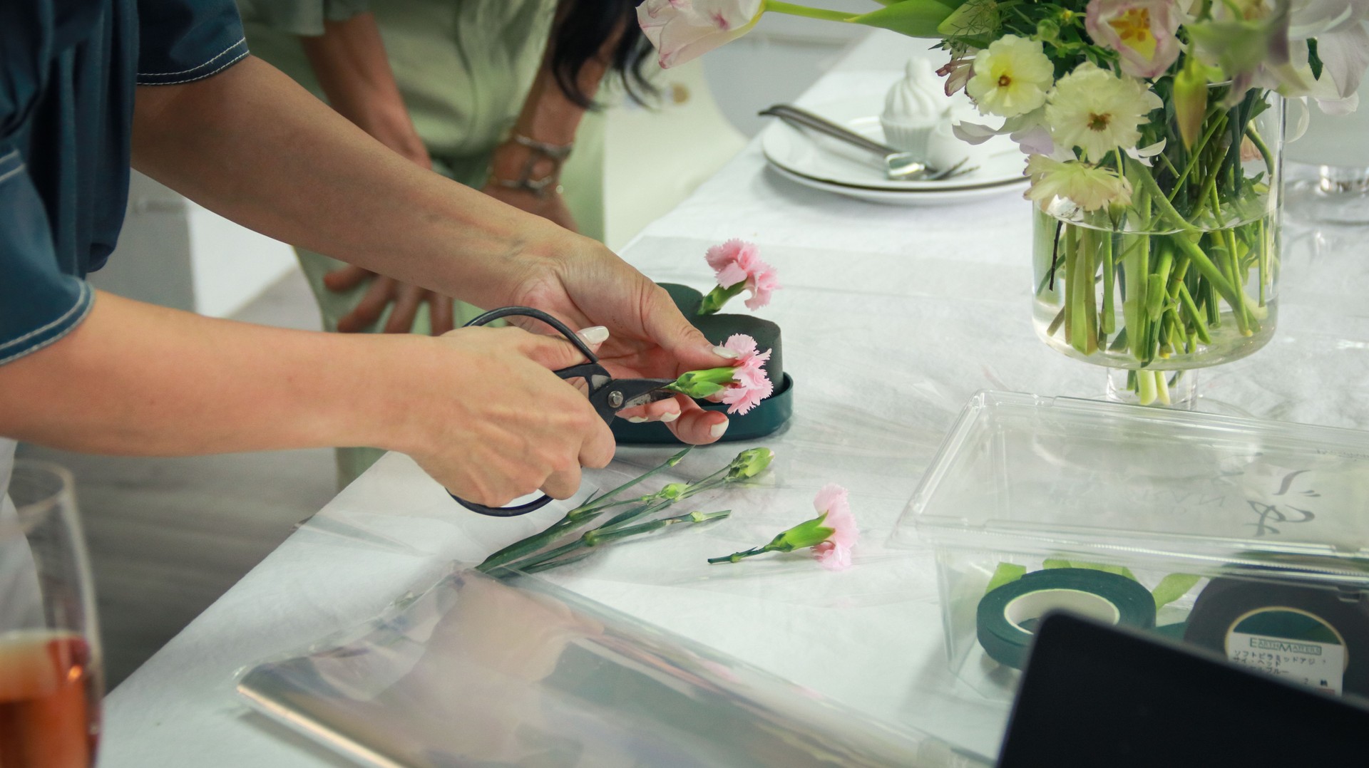 A beautiful Asian floral art teacher is demonstrating the techniques of flower arrangement to the floral art students.